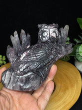 Load image into Gallery viewer, Crystal carvings of a bird and a dragon held by a hand against a dark background.
