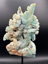 Load image into Gallery viewer, Carved sky blue quartz piece with floral design on a dark background
